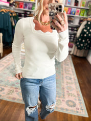 Ivory knit top with long sleeves and scalloped scoop neckline.