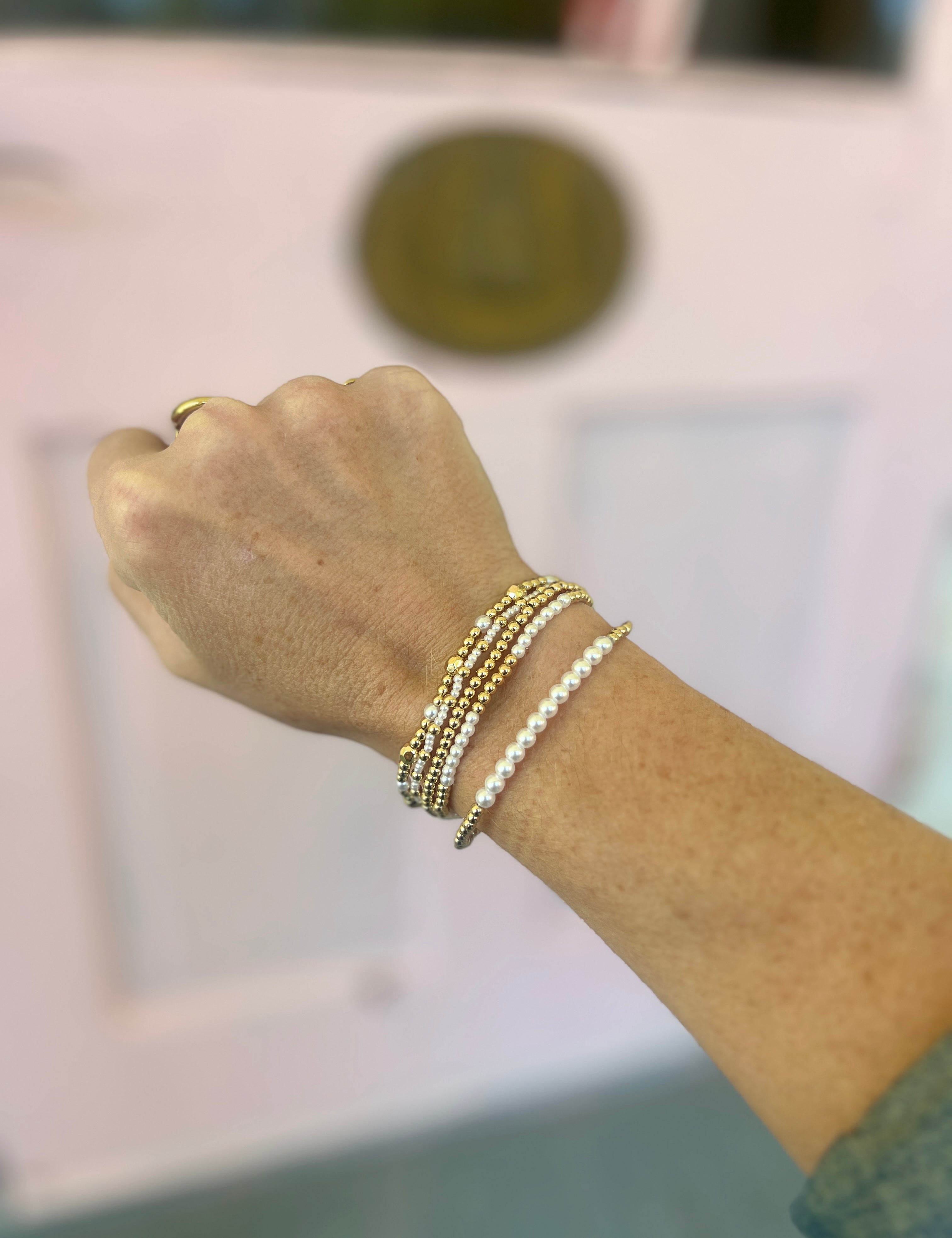 Gold-tone bracelet set with white pearl-like beaded cuffs and elastic chain links