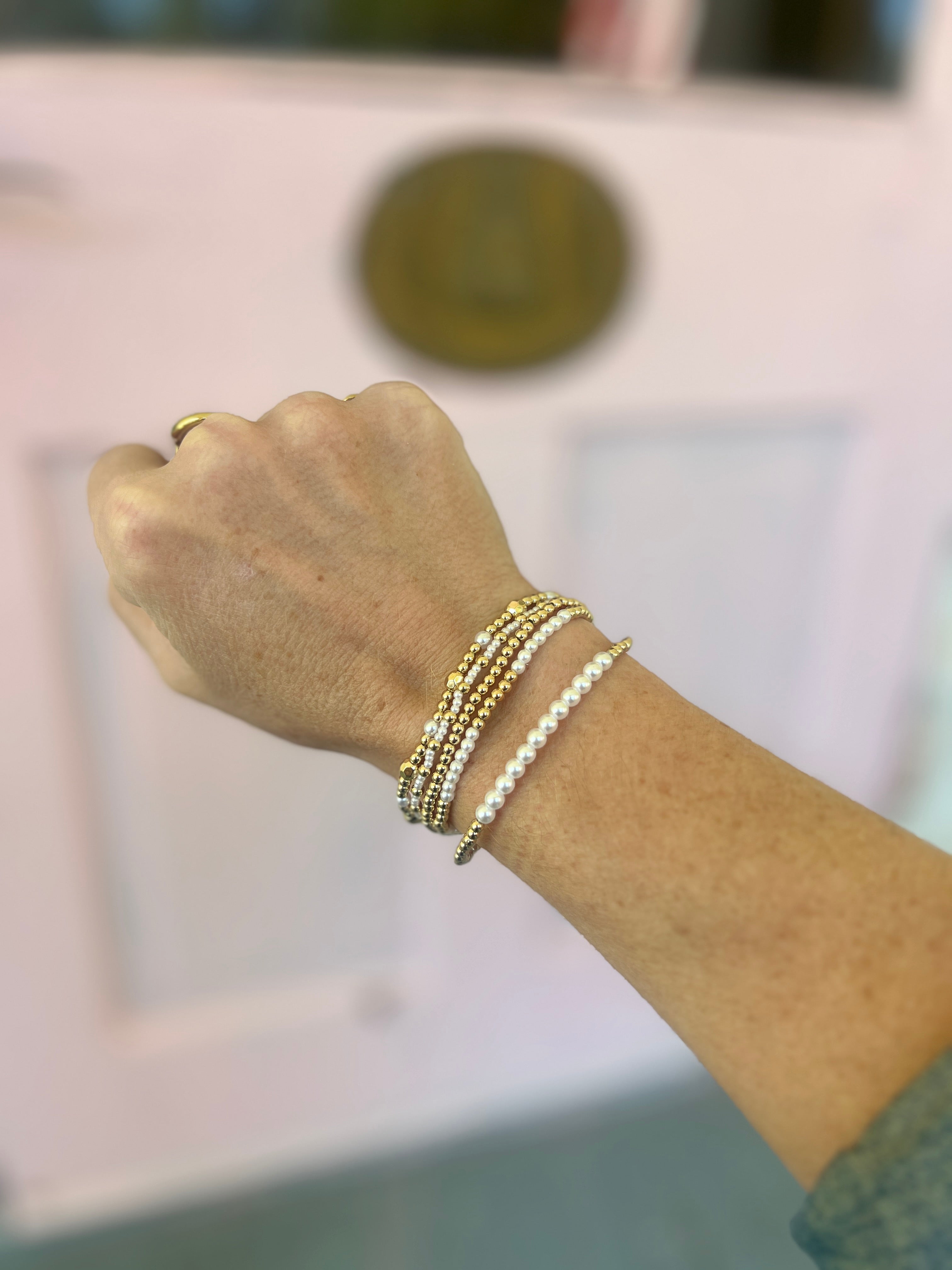 Gold-tone bracelet set with white pearl-like beaded cuffs and elastic chain links