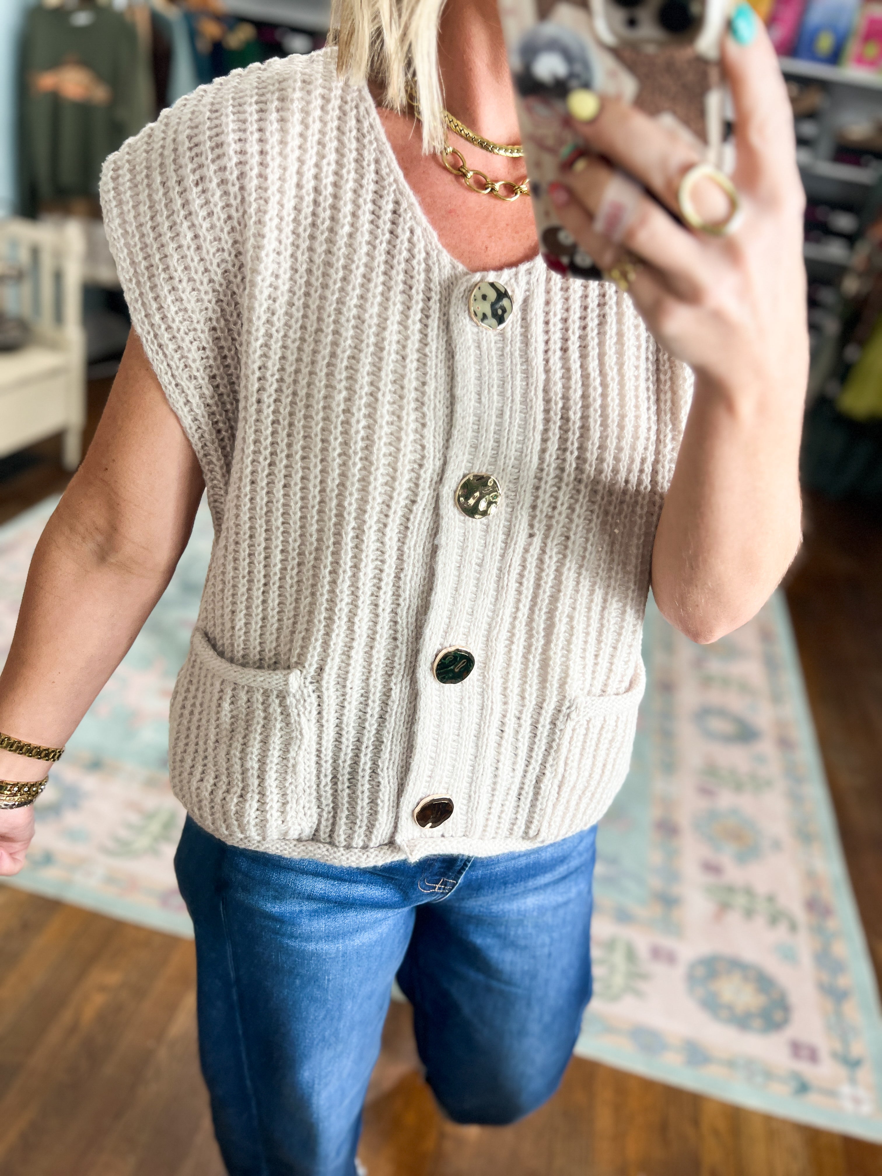 Beige knit sweater vest with V-neck and dark buttons, sleeveless close-up