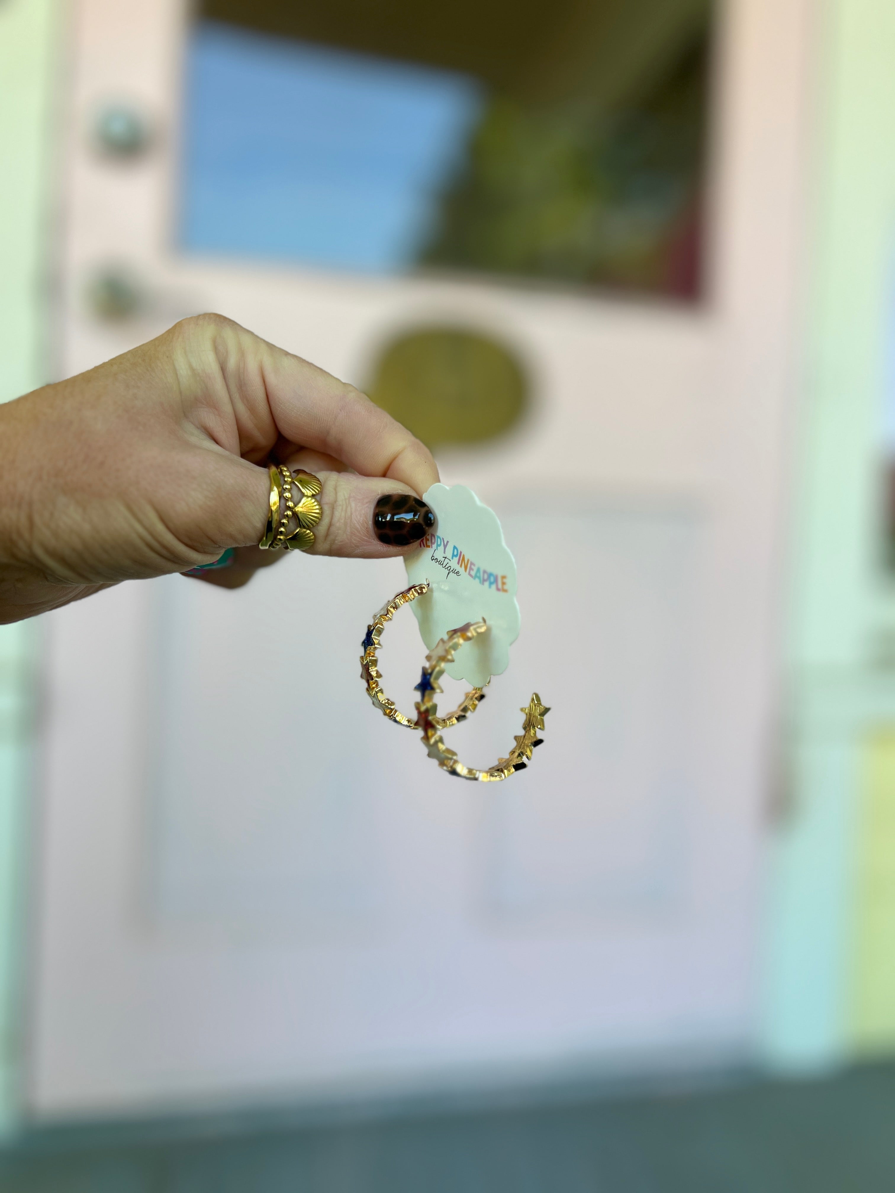 Gold-tone star hoop earrings with red, white, and blue epoxy stars