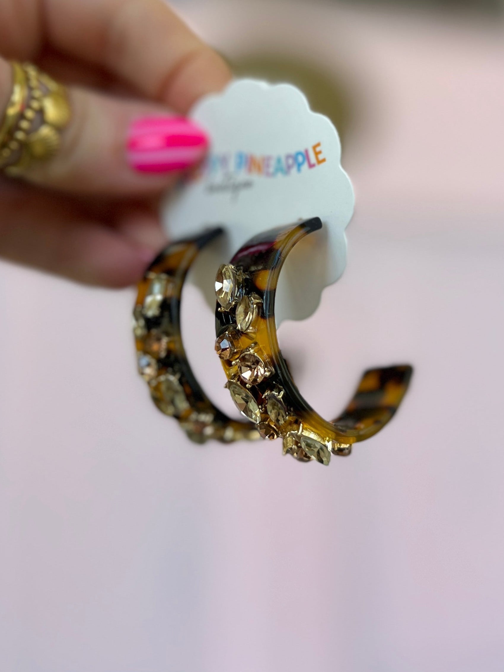 Curved gold-tone acetate hoop earrings with amber glass-stone cluster accents