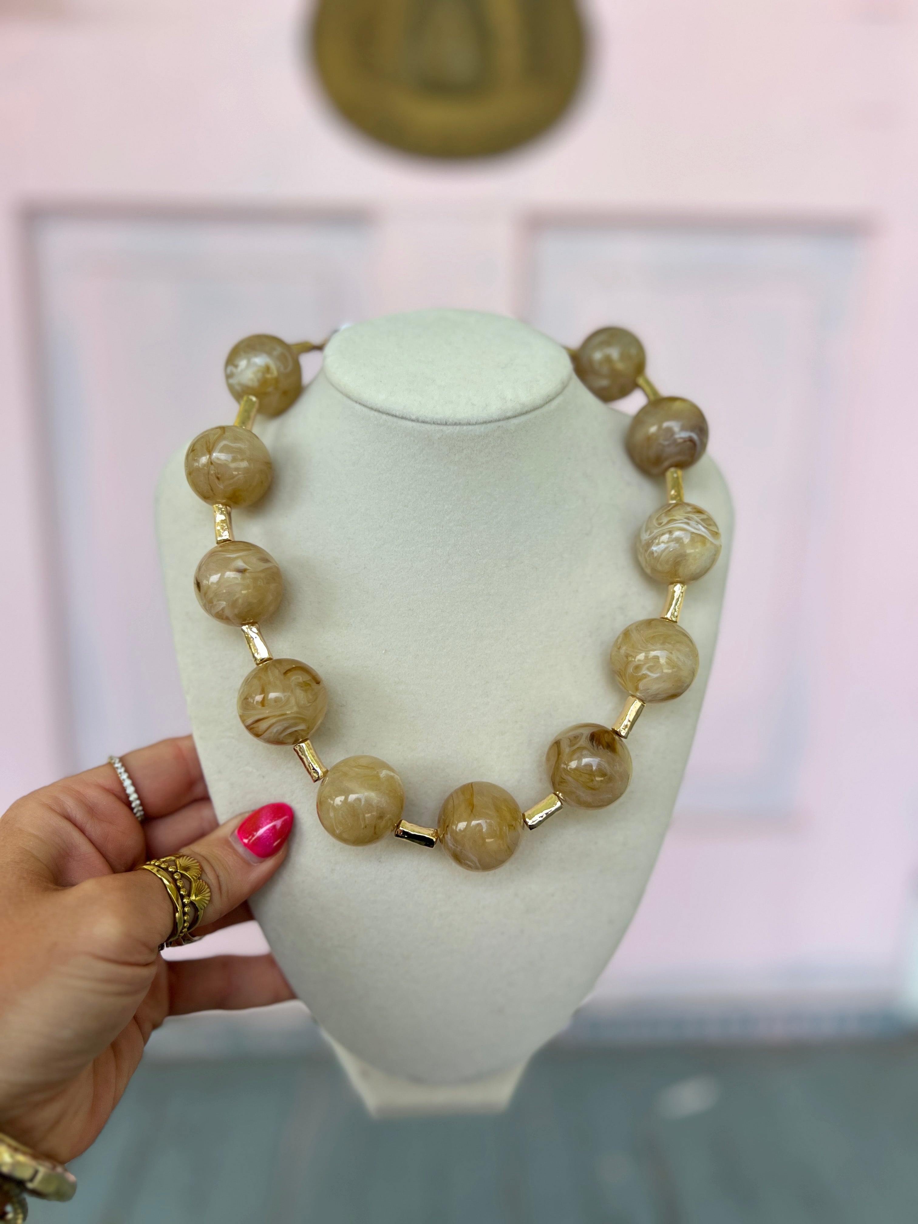 Natural marble ball and bar necklace with gold-tone bead accents on a collar display
