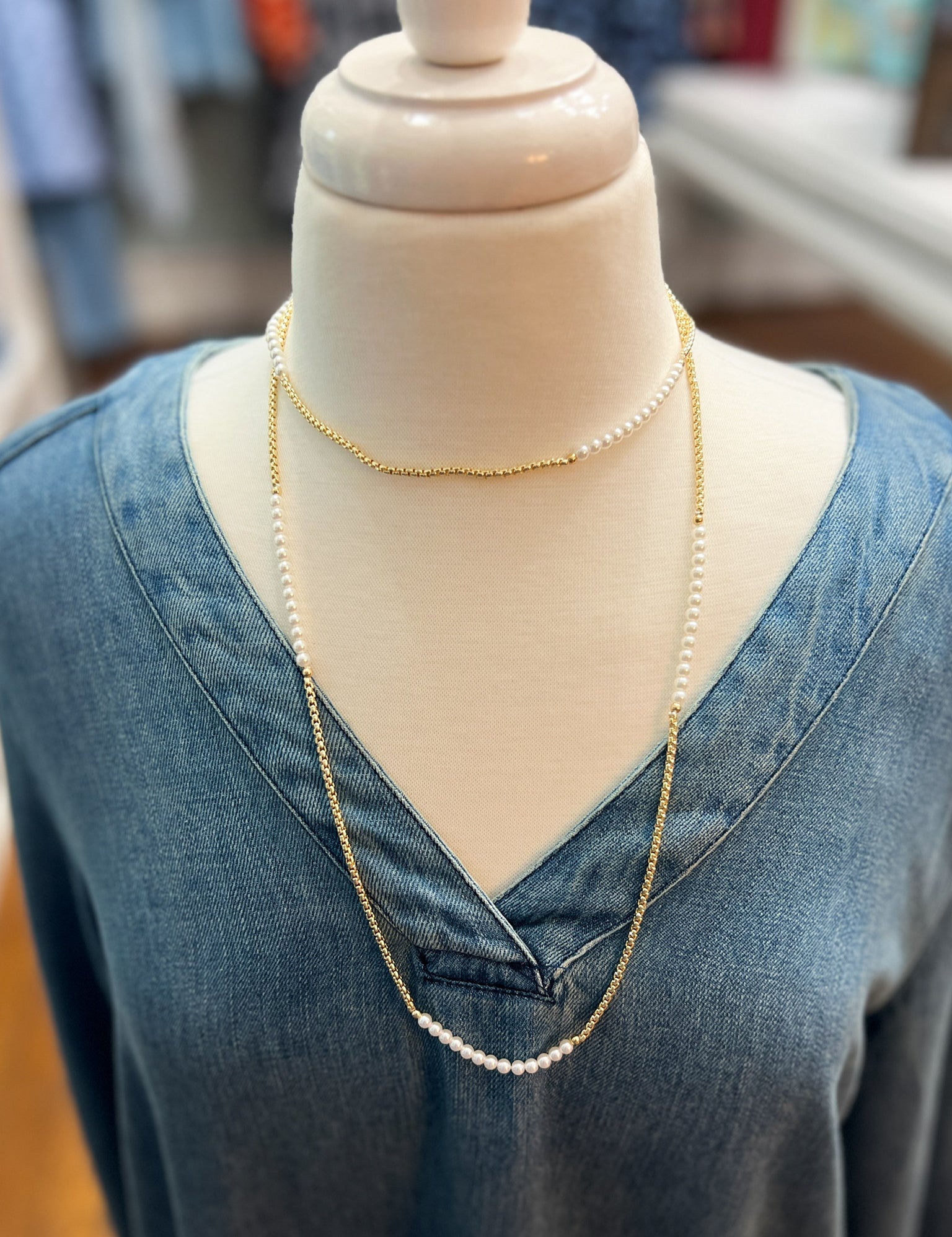 Layered gold-tone necklace with small pearl bead strands, V-shaped on mannequin