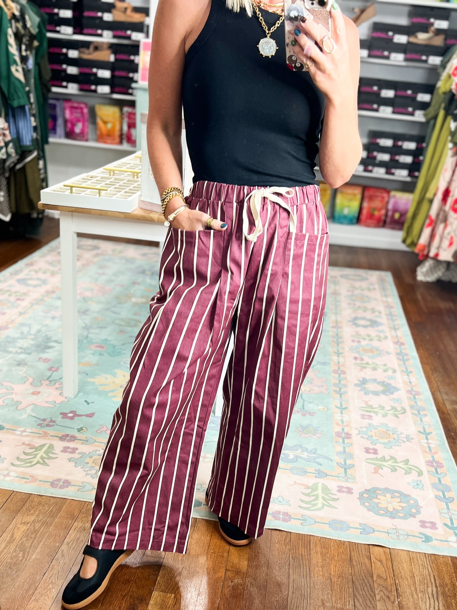 Burgundy wide-leg striped pants with white vertical stripes and side pockets