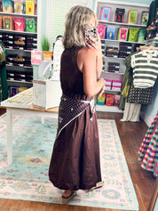 Back view of brown sleeveless midi dress with polka-dot draped waist panel