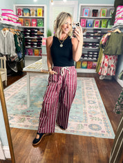 Burgundy striped wide-pocket pants with white vertical stripes and relaxed wide legs
