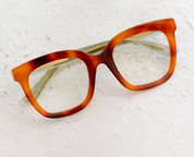 Orange tortoise-effect eyeglass frames with green inner accents, angled view