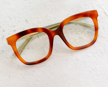 Orange tortoise-effect eyeglass frames with green inner accents, angled view
