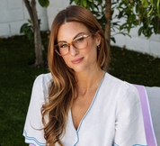 Peepers tan eyeglasses on a person with long hair, front view