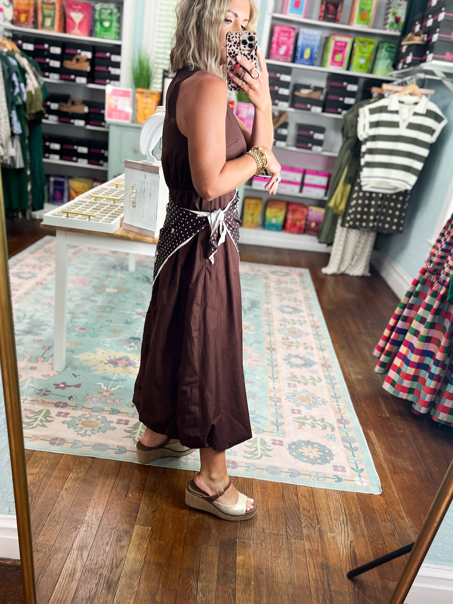Side view of brown sleeveless midi dress with polka-dot draped sash detail