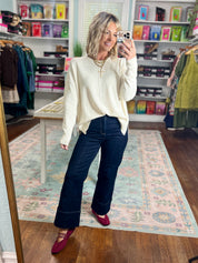 Cream roll-neck seam-detail sweater, side-front view with long sleeves