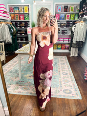 Burgundy strapless maxi dress with large cream and pink flower print along the bodice and skirt