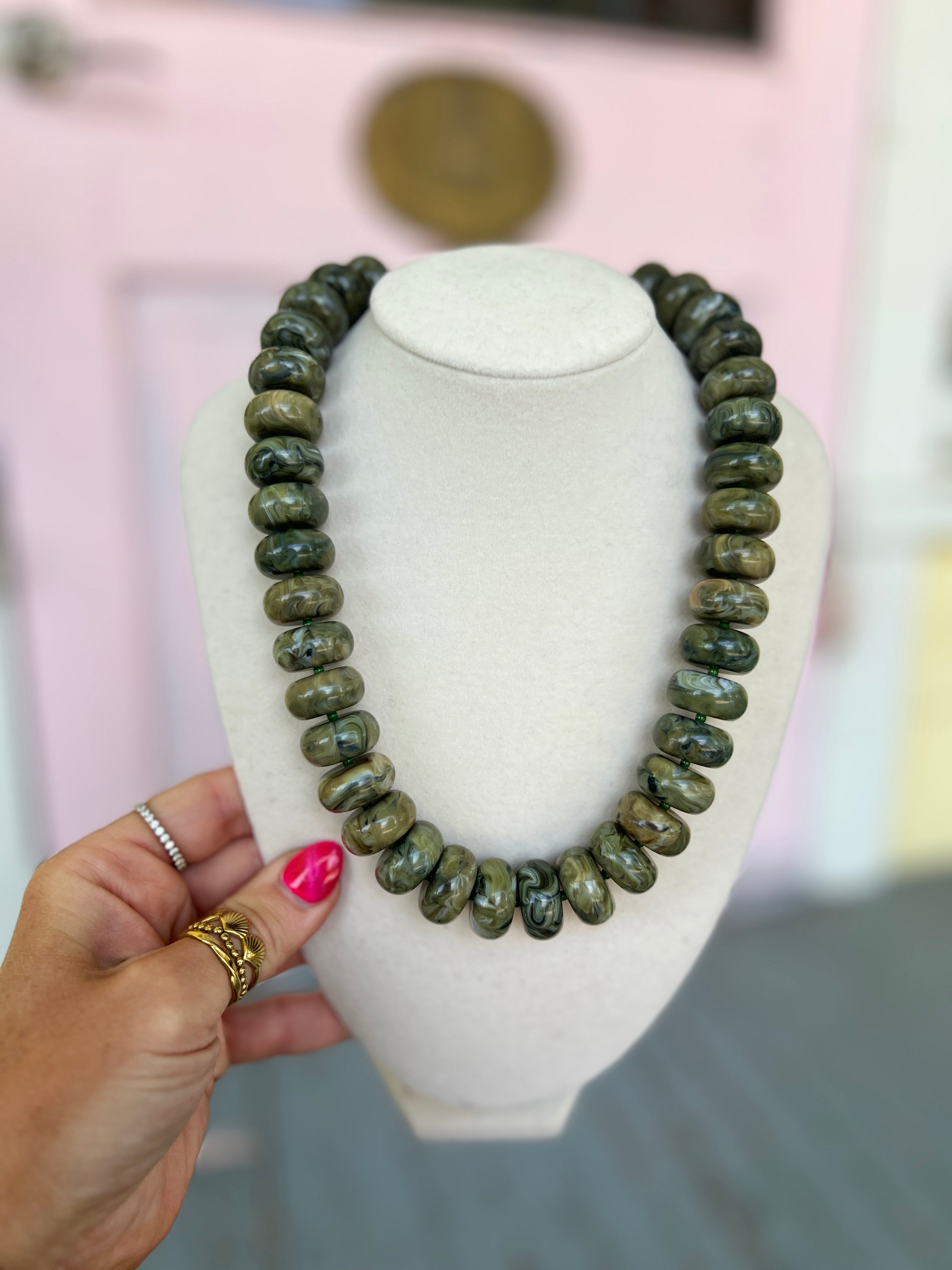 Olive marble rondelle bead necklace on a white jewelry display bust