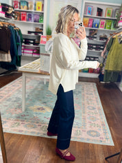 Cream roll-neck seam-detail sweater, back view over shoulder