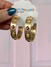 Gold-tone hoop earrings with red square charm and small round station stones