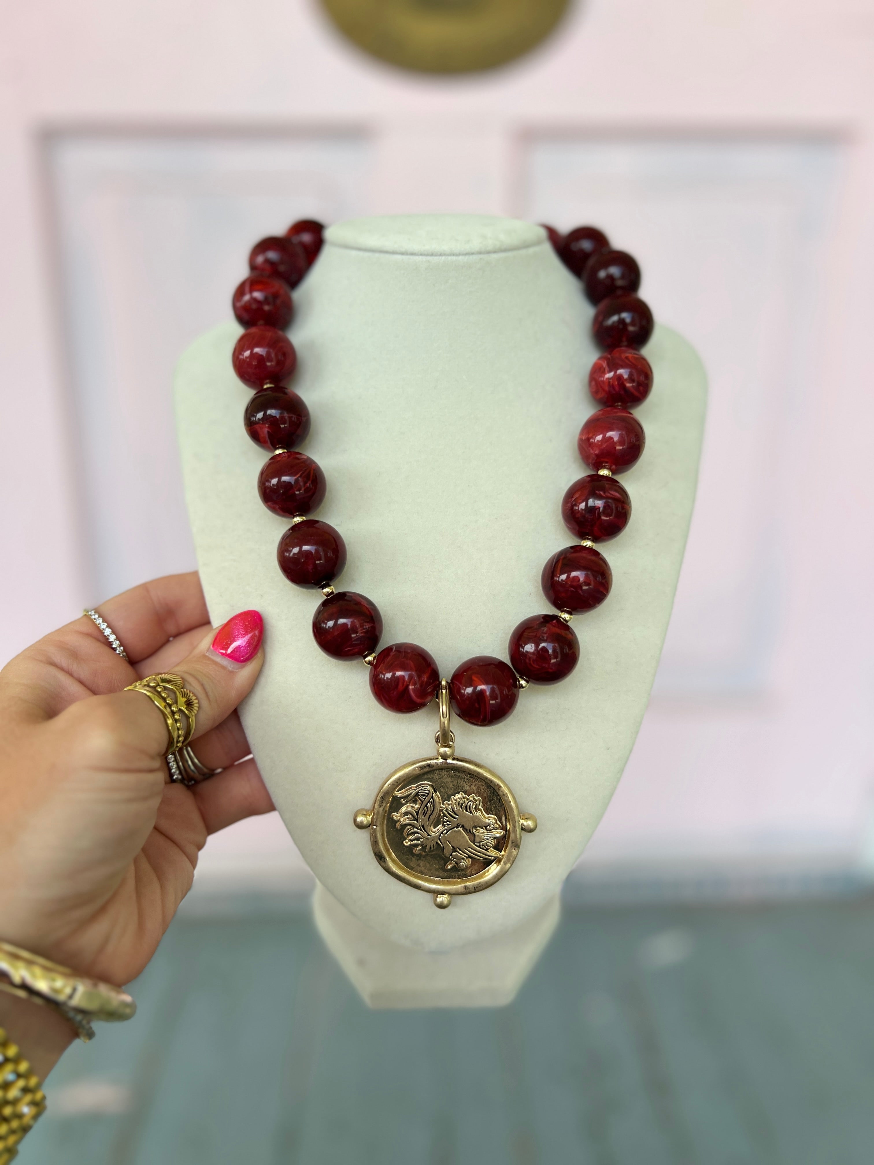 Burgundy acrylic marble bead necklace with round gold-tone medallion pendant