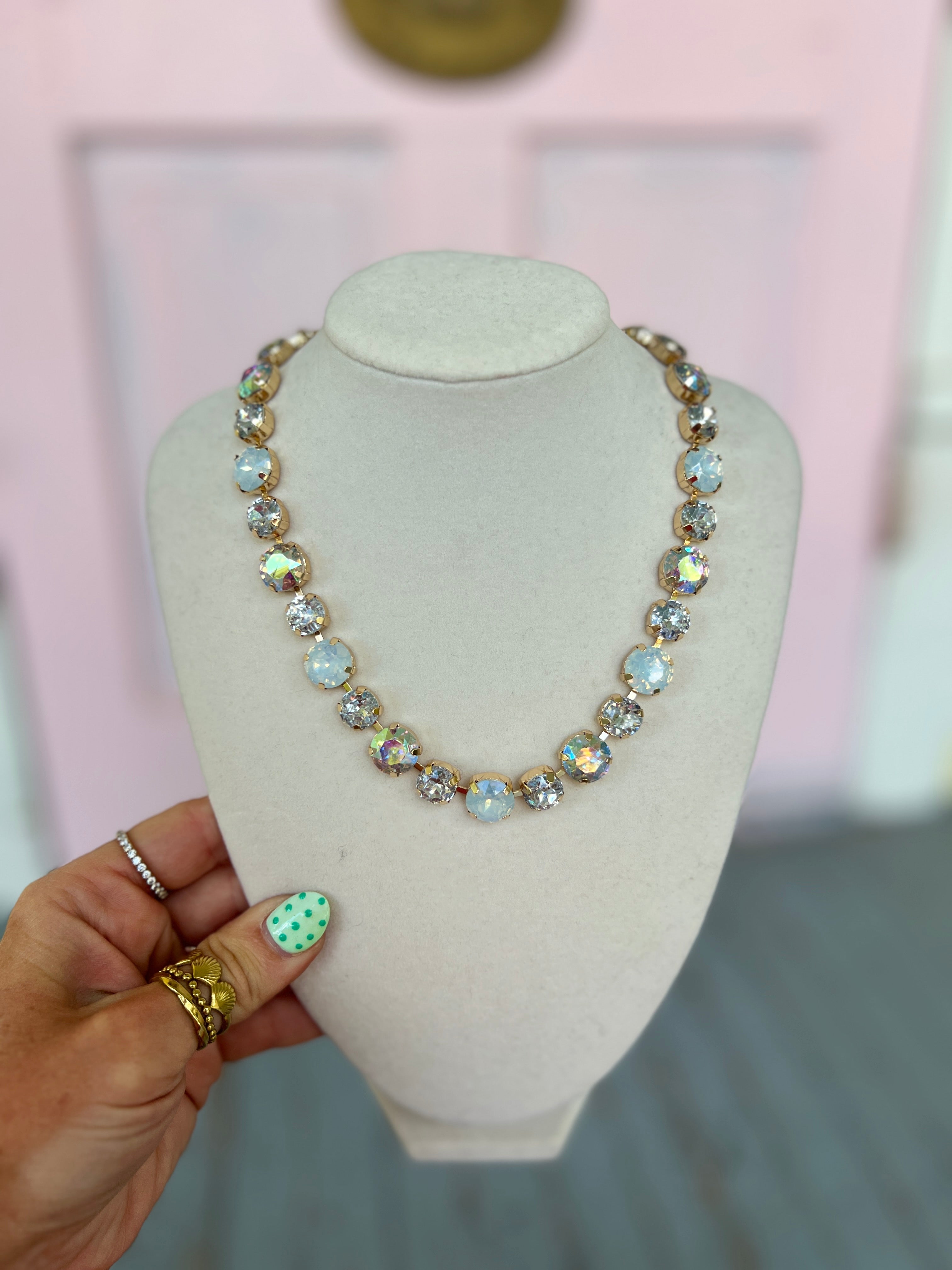 Iridescent glass bead magnetic necklace with gold-tone round beads, front view on stand
