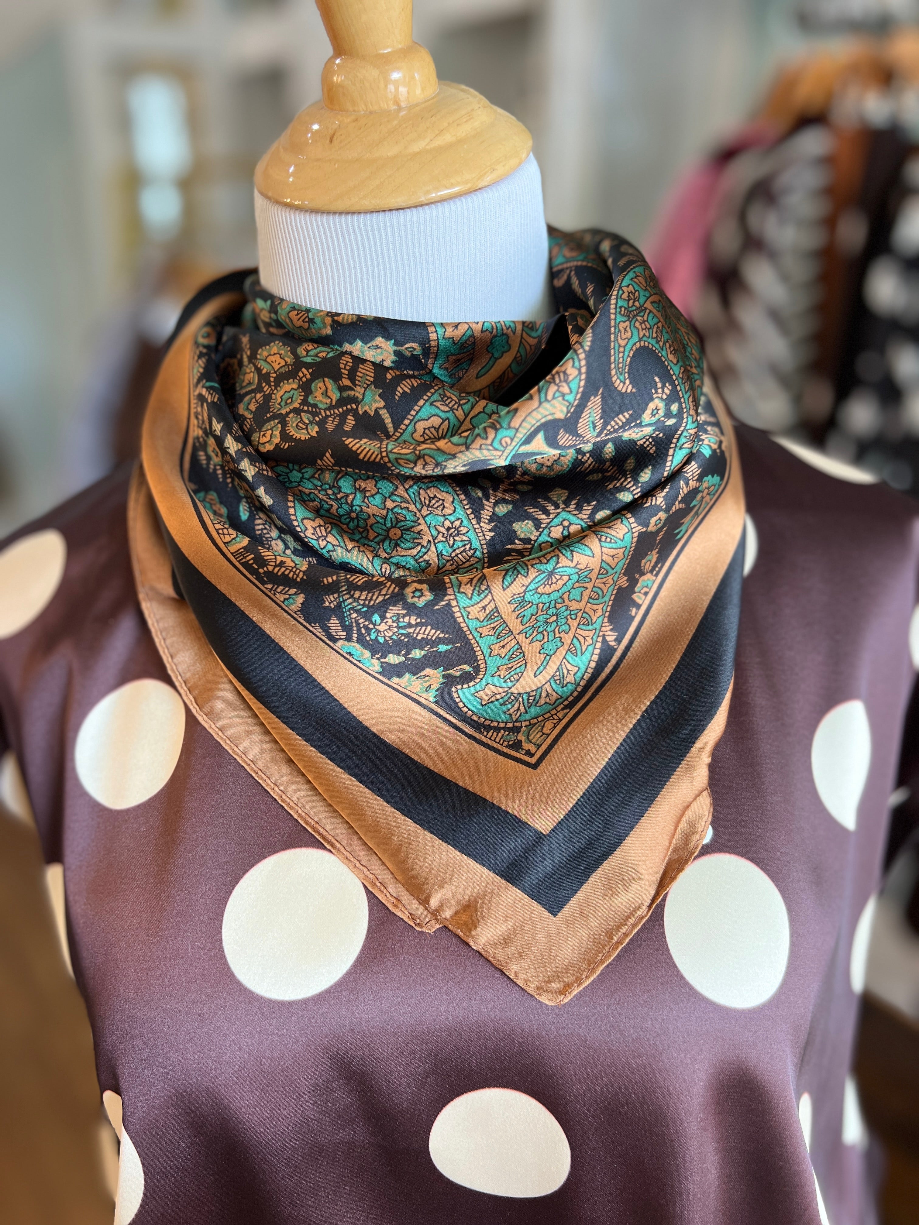 Green and black paisley bandana scarf with tan border, folded triangle