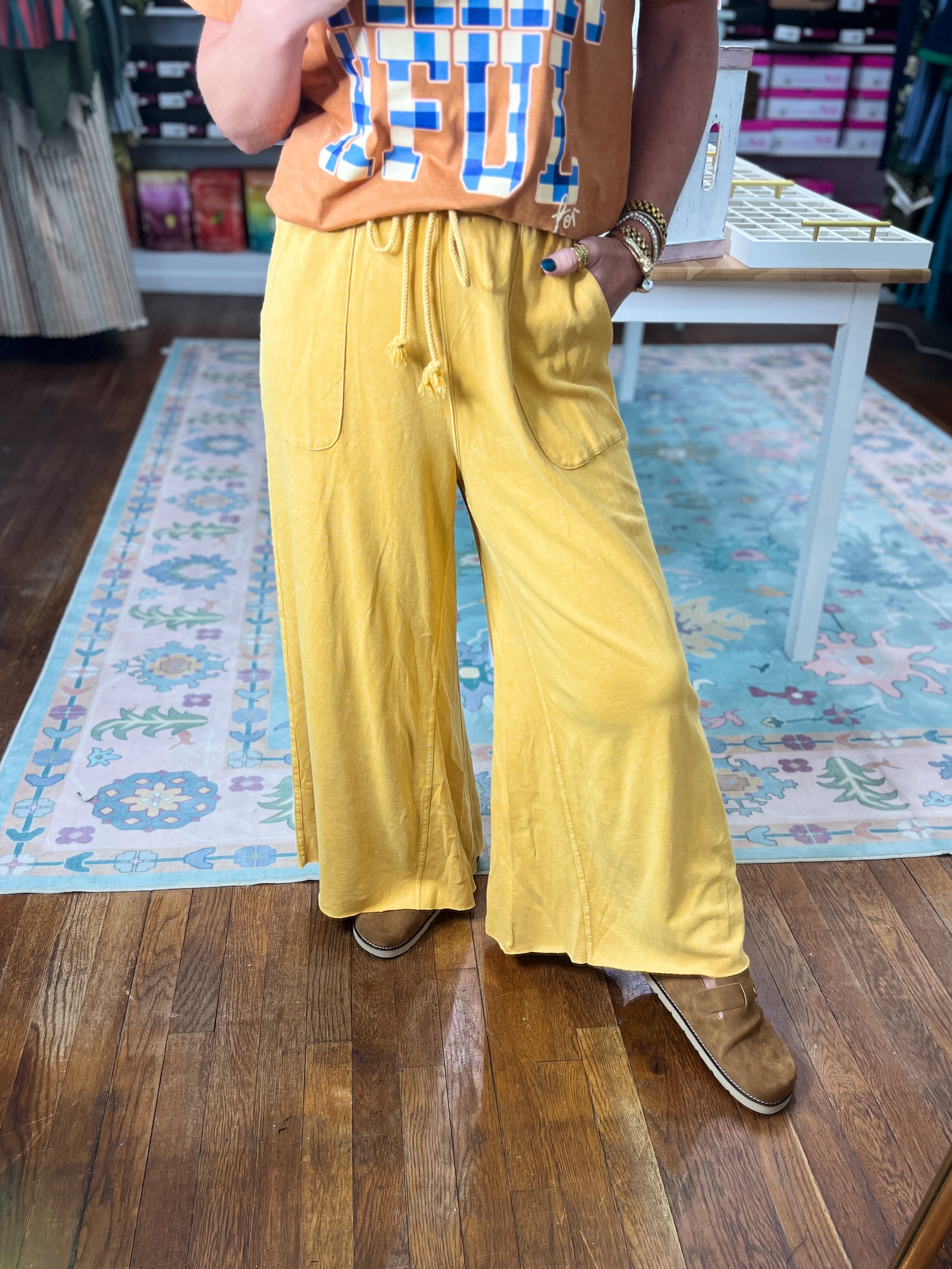 Mustard wide-leg pants with drawstring waist and side pockets, flowing drape.