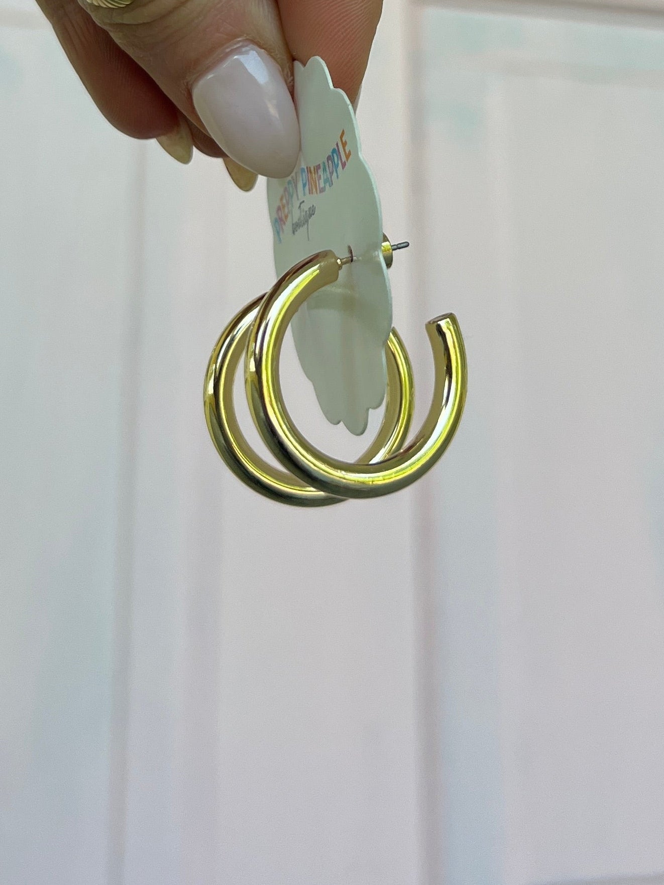 Gold metal hoop earrings with stacked rings on silver post, close-up