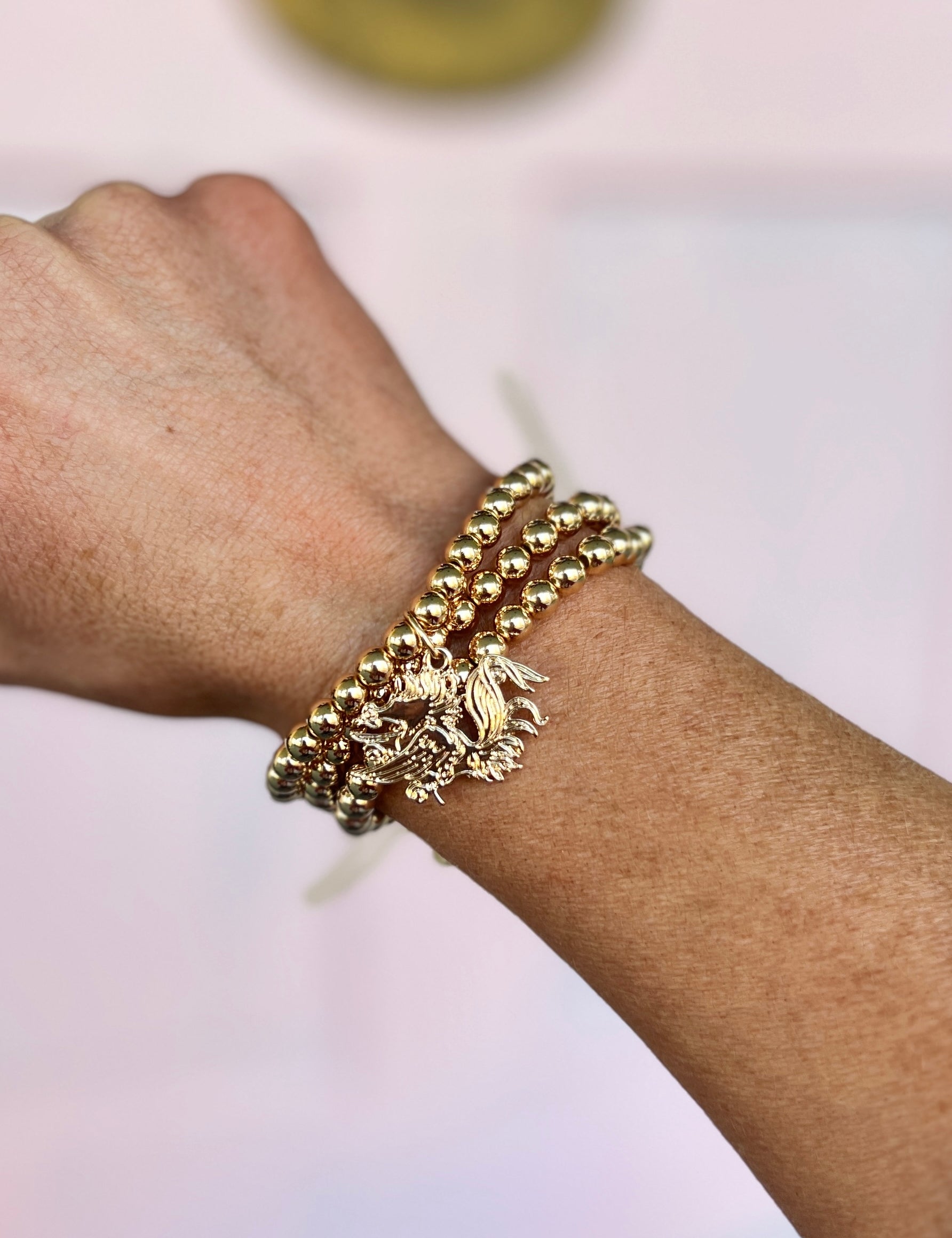 Gold beaded charm bracelet with rooster-shaped pendant and braided bead links