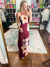 Burgundy strapless maxi dress with large cream and pink flowers, fitted bodice and long skirt
