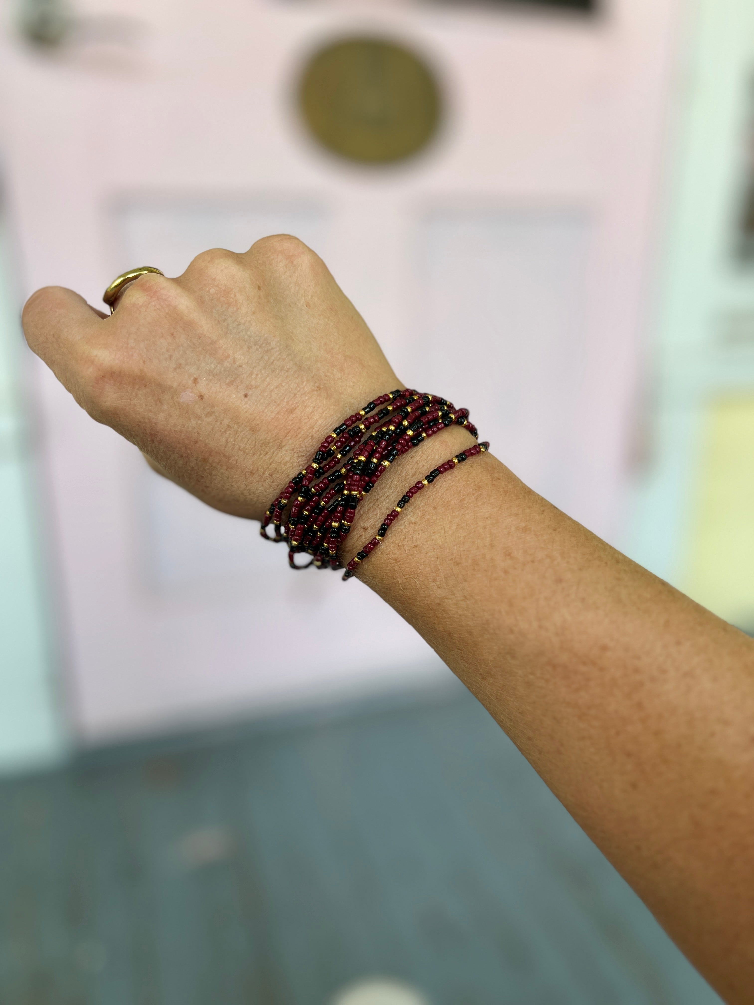 Multi-row seed bead bracelet set in burgundy and black on wrist