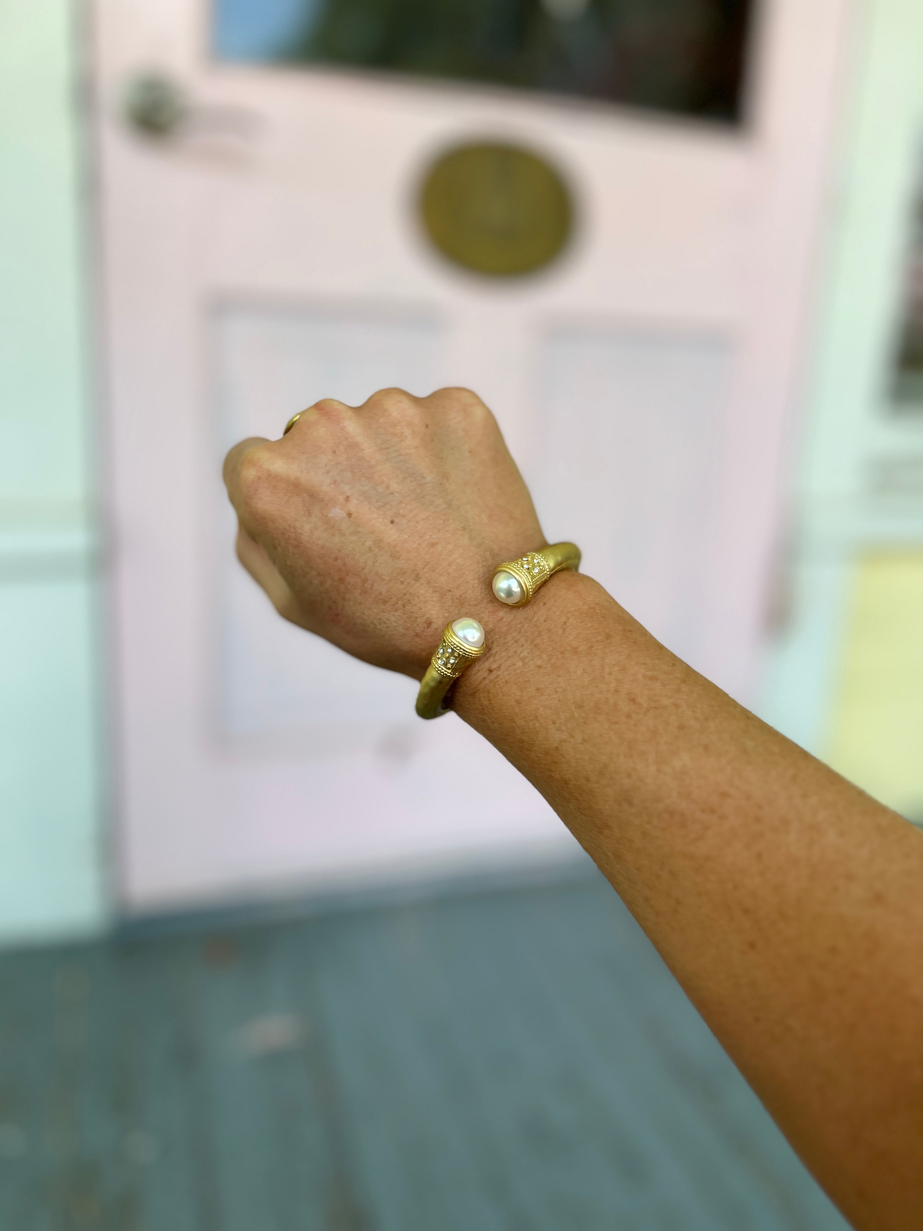 Gold hammered cuff bracelet with two pearl-bead details on the wrist