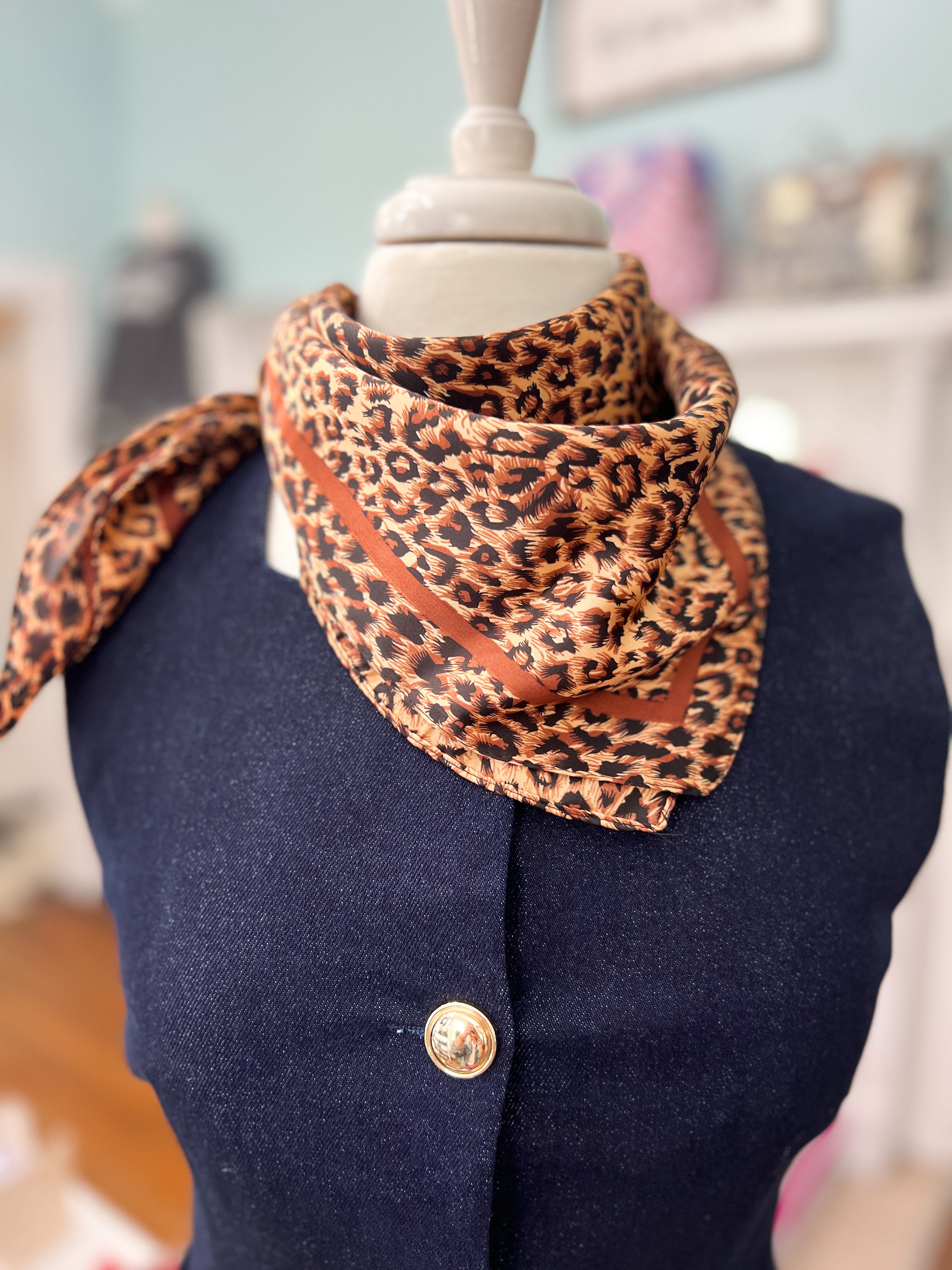 Silky leopard-print bandana in gold tones, folded around a mannequin neck