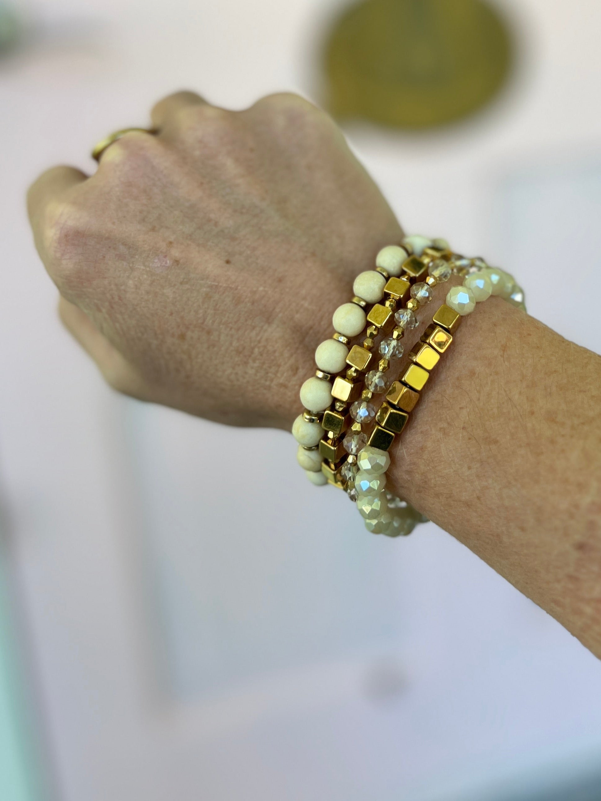Natural bead bracelet on wrist with pale green stones and gold-tone accents
