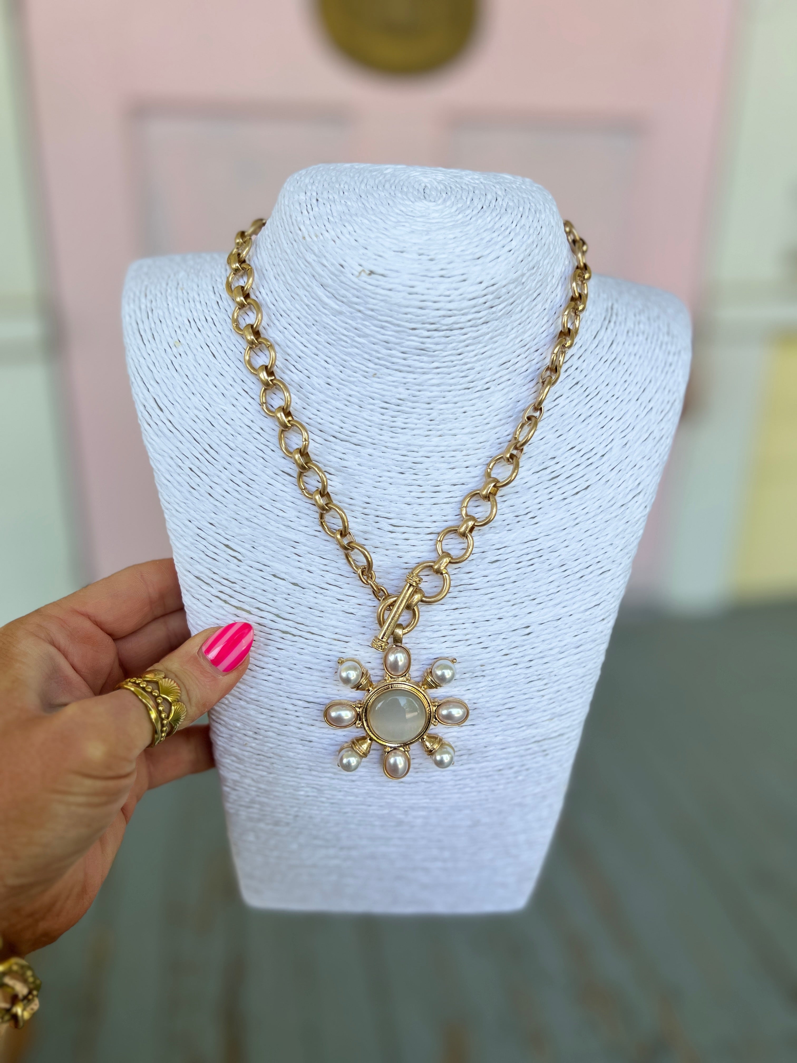 Gold necklace with pearl-like round stones and a flower-shaped pendant