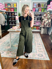 Olive patterned twill overalls with adjustable straps and wide, straight pant legs