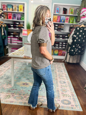 Striped short sleeve V-neck top with brown neckline trim, worn with jeans