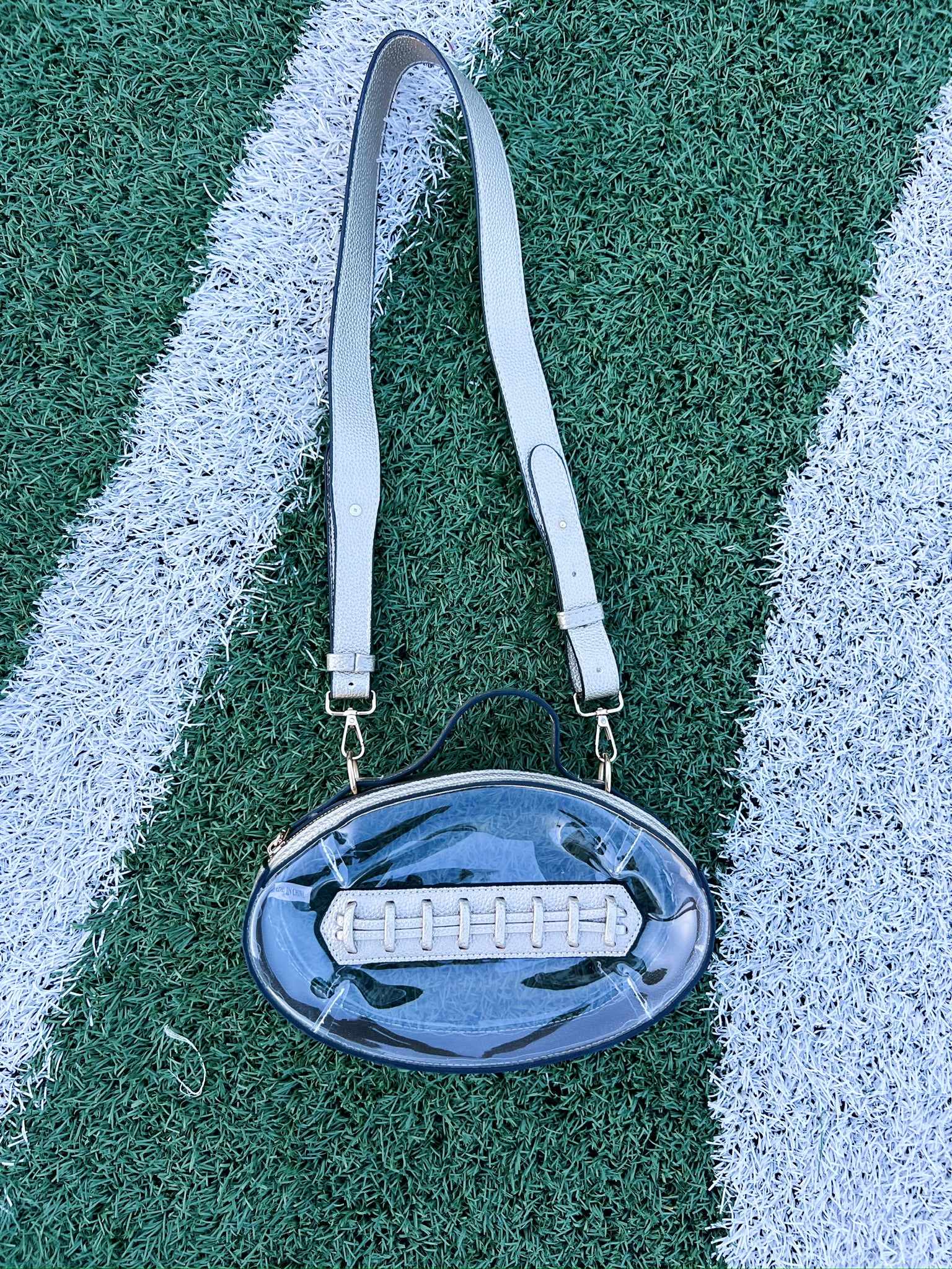 Clear oval football-themed crossbody bag with adjustable straps and zipper top