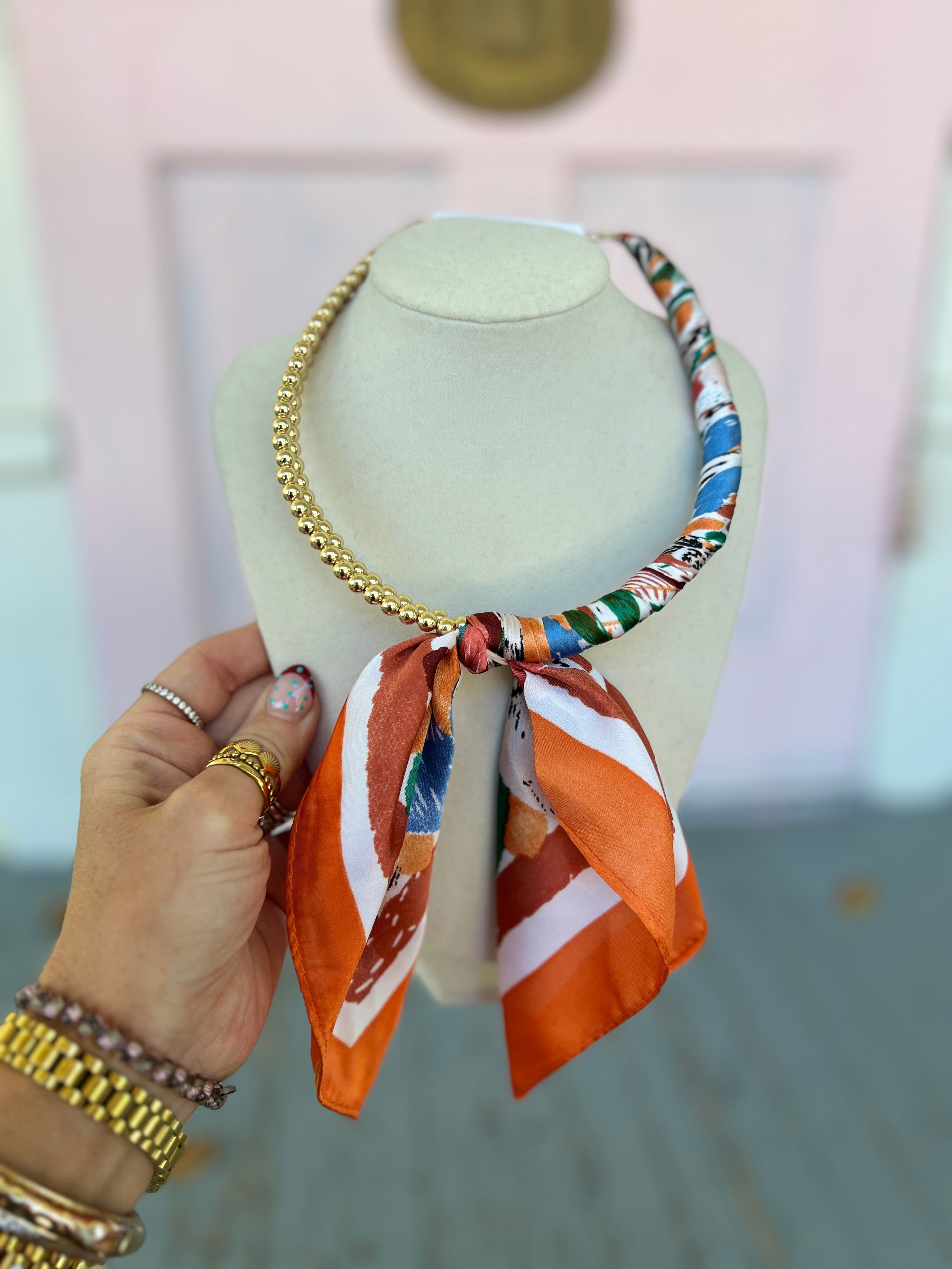 Scarf-wrapped collar necklace with gold chain and orange multi striped bow
