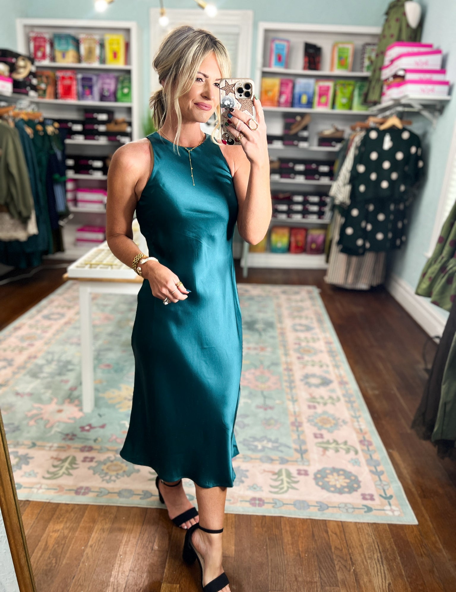 Dark teal satin midi dress with sleeveless cut, high neckline, and straight midi hem.
