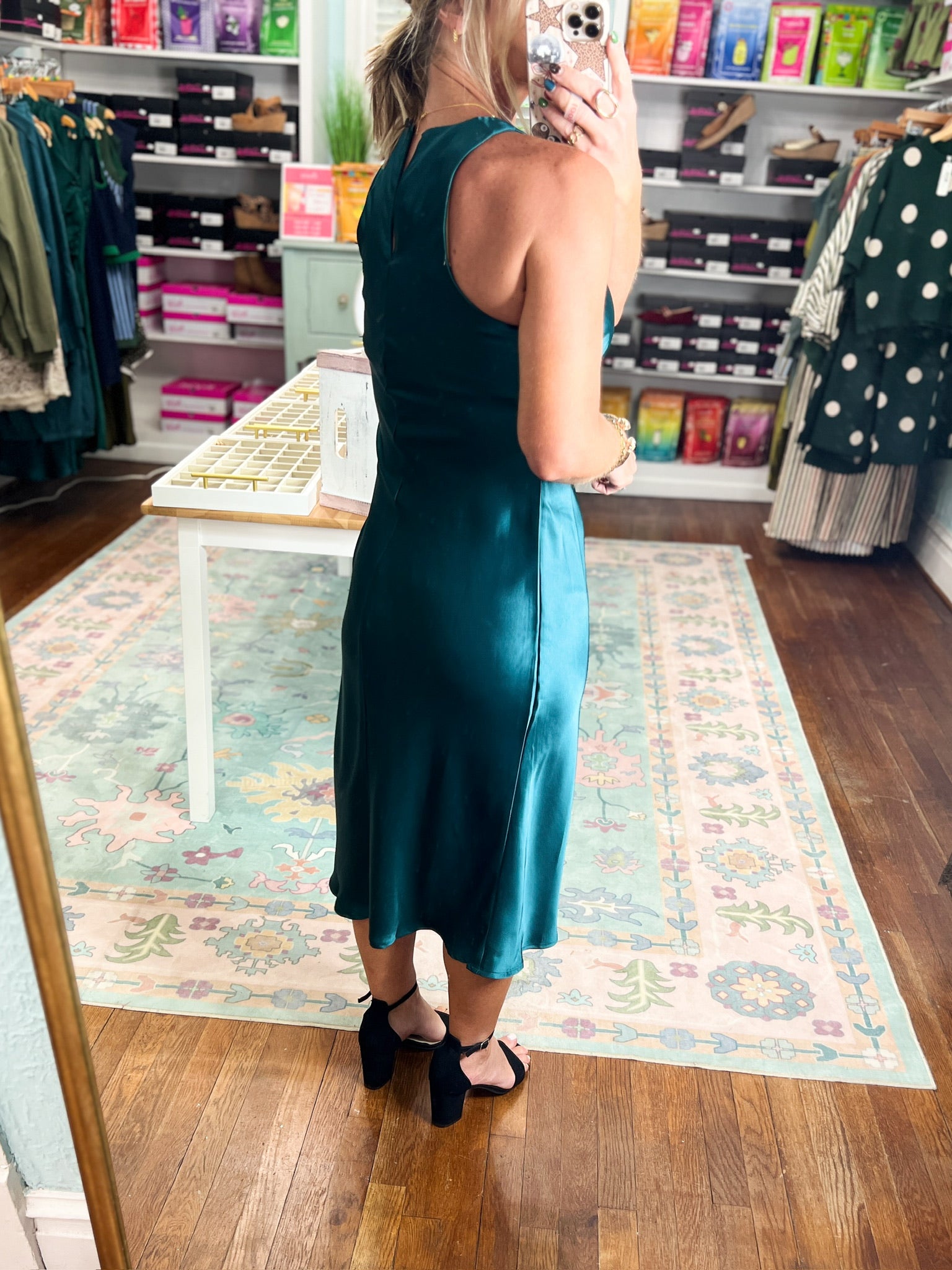 Dark teal satin midi dress viewed from back, sleeveless with button detail.