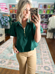 Hunter green puff-sleeve top with half-zip neckline and gold zipper