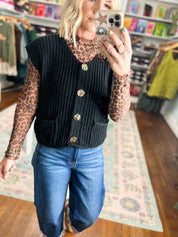 Black textured knit button-front sweater vest with rounded gold buttons