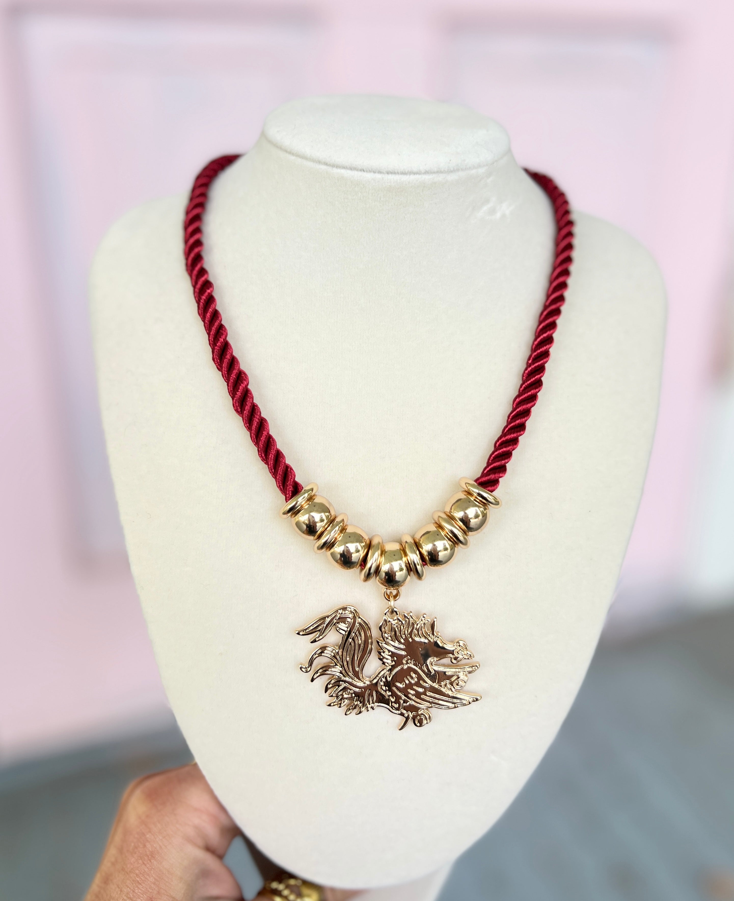 Burgundy braided cord necklace with gold beads and rooster emblem pendant