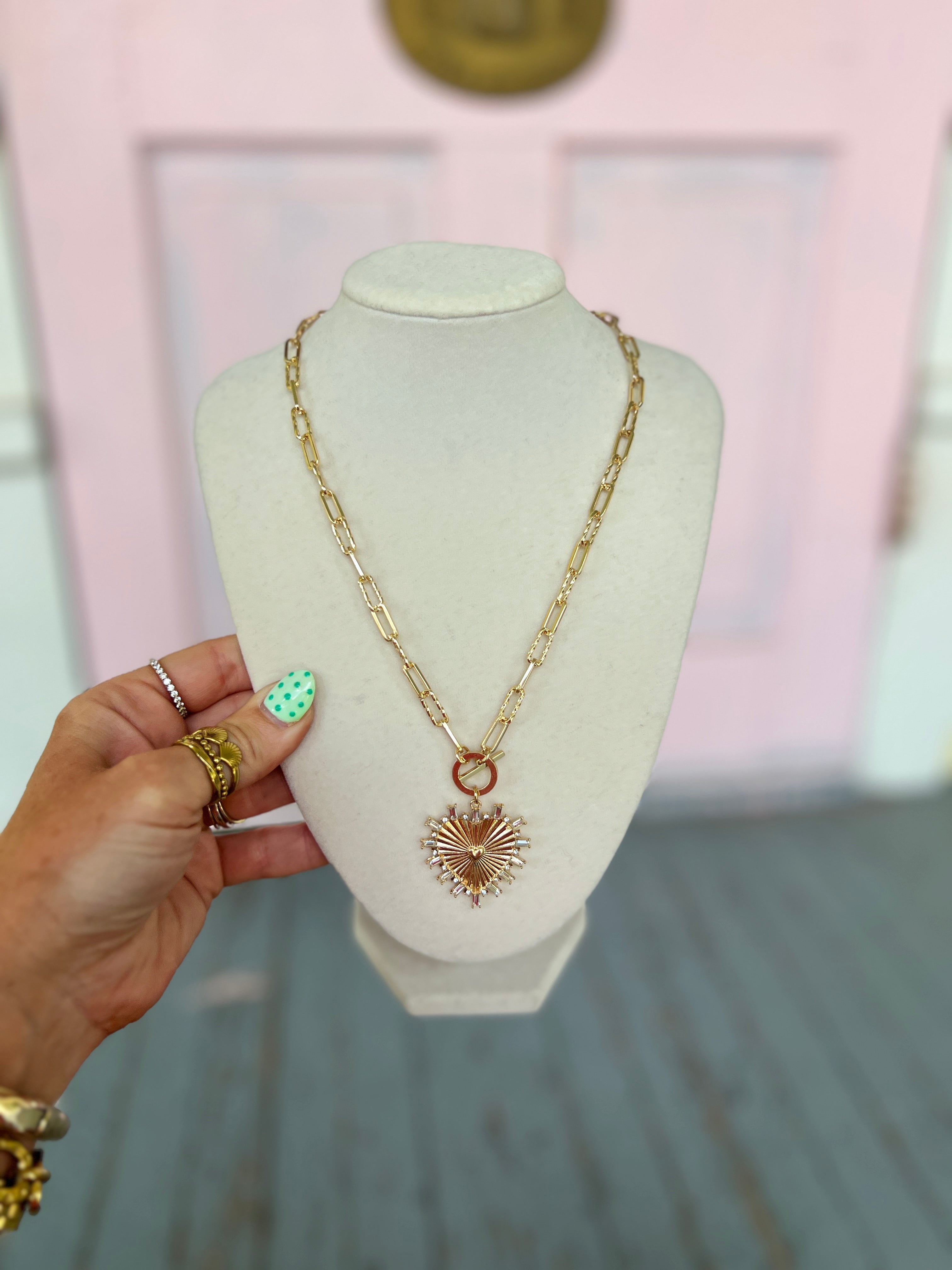 Gold-tone heart pendant necklace set with red center and textured drop