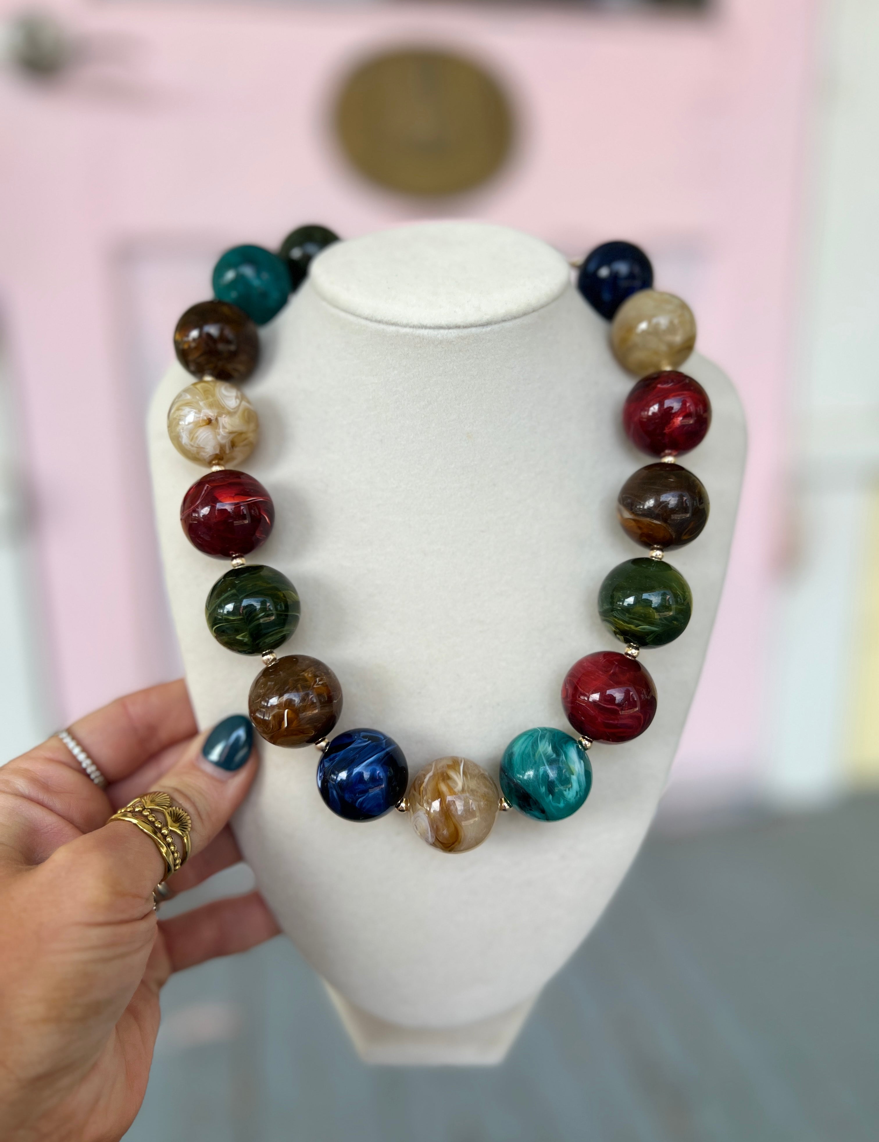 Marble acrylic bead necklace with multicolor round beads on a display bust