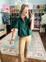 Hunter green puff-sleeve top with half-zip and gold zipper detail