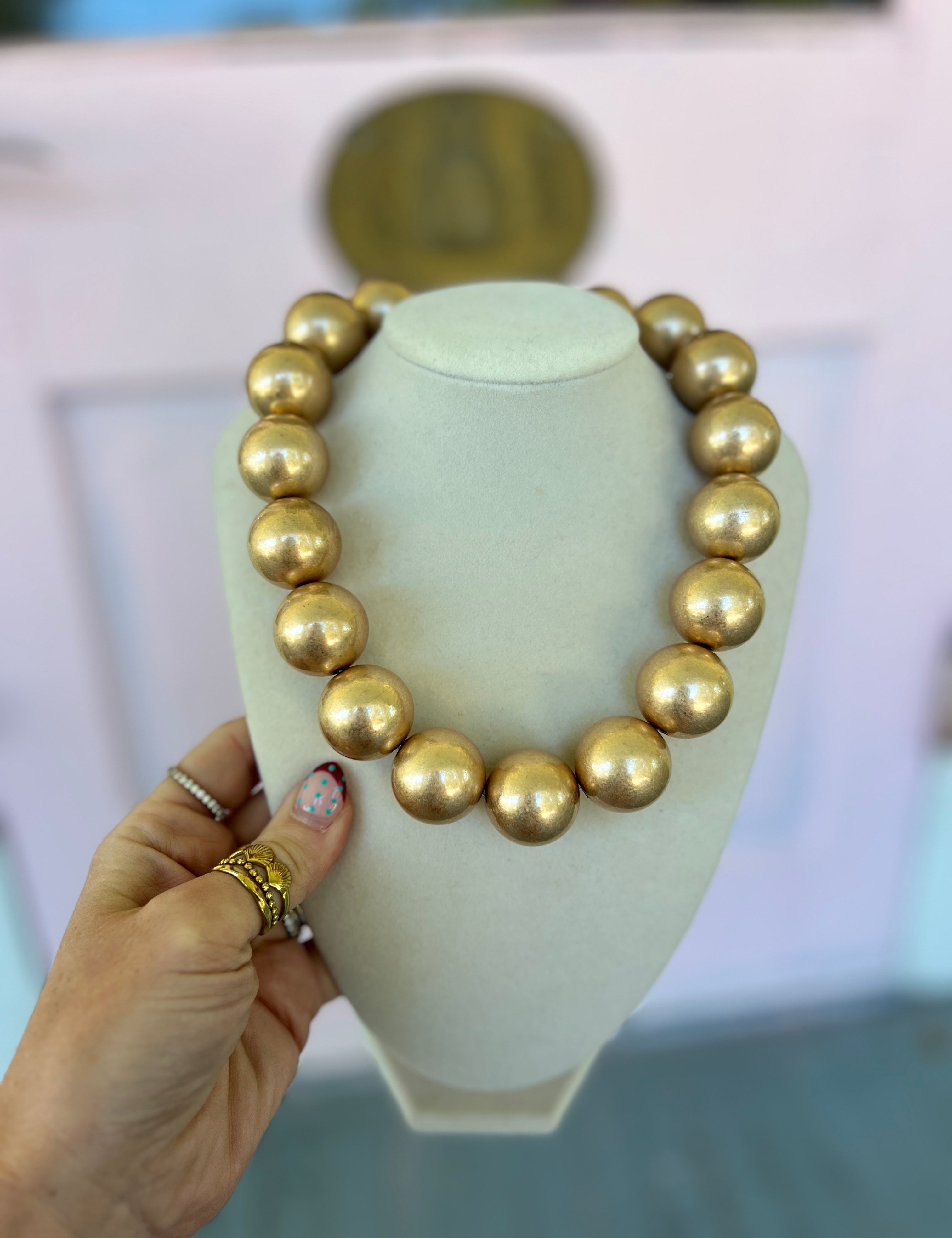 Gold-tone round ball bead necklace on a necklace stand