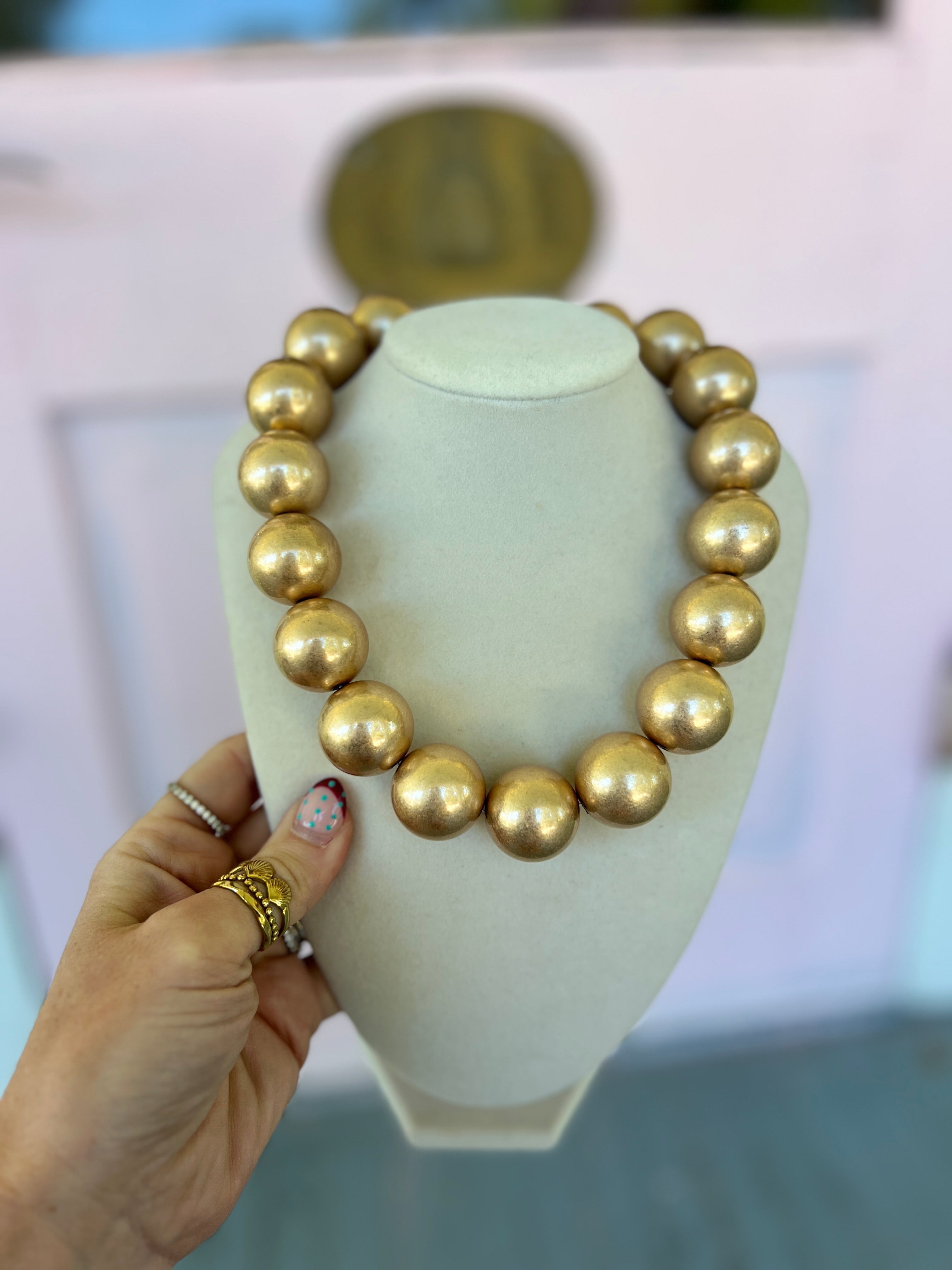 Gold-tone round ball bead necklace on a necklace stand