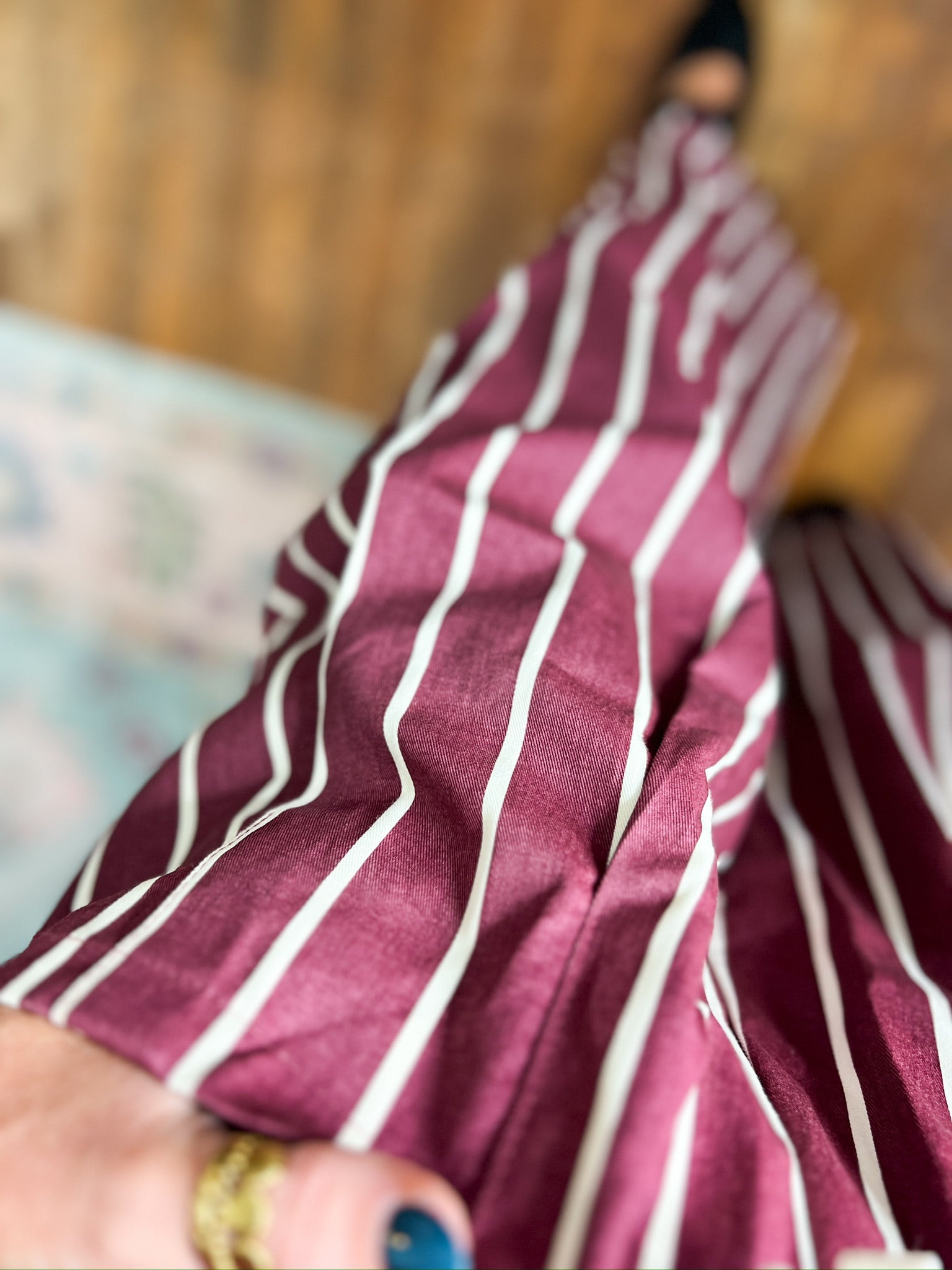 Close-up of burgundy striped wide-leg pants fabric with white vertical stripes