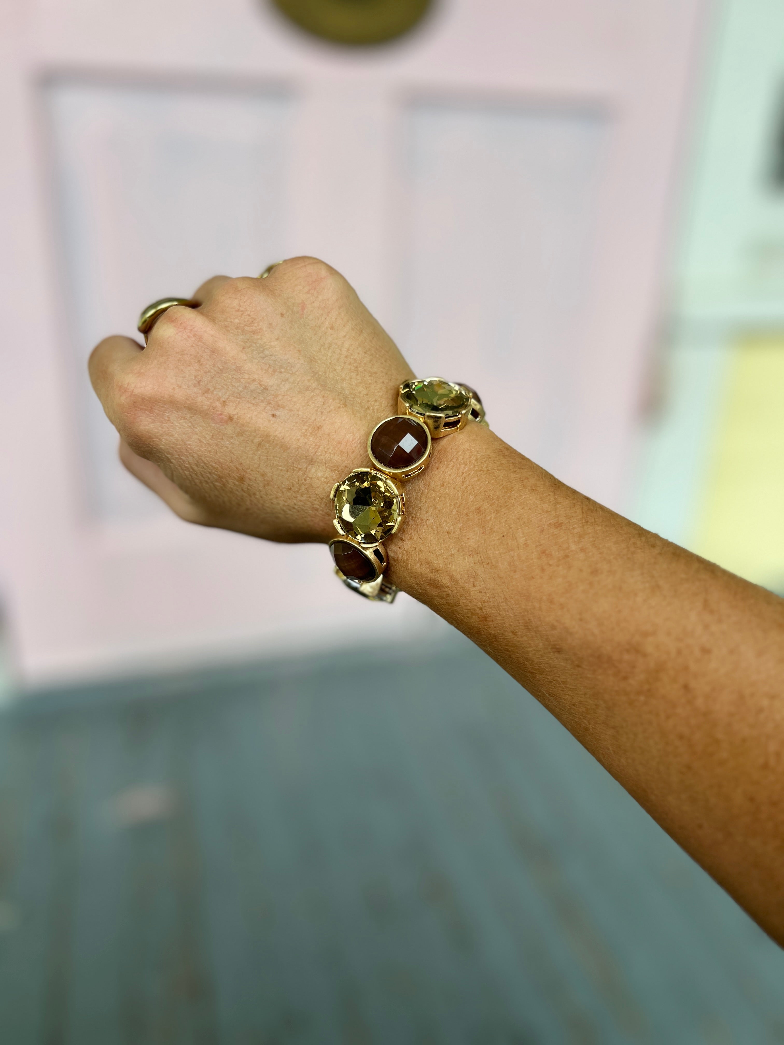 Gold-tone elastic bracelet with dark green round epoxy stone beads on a wrist