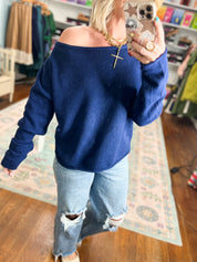 Navy off-shoulder sweater with gold cross detail at neckline