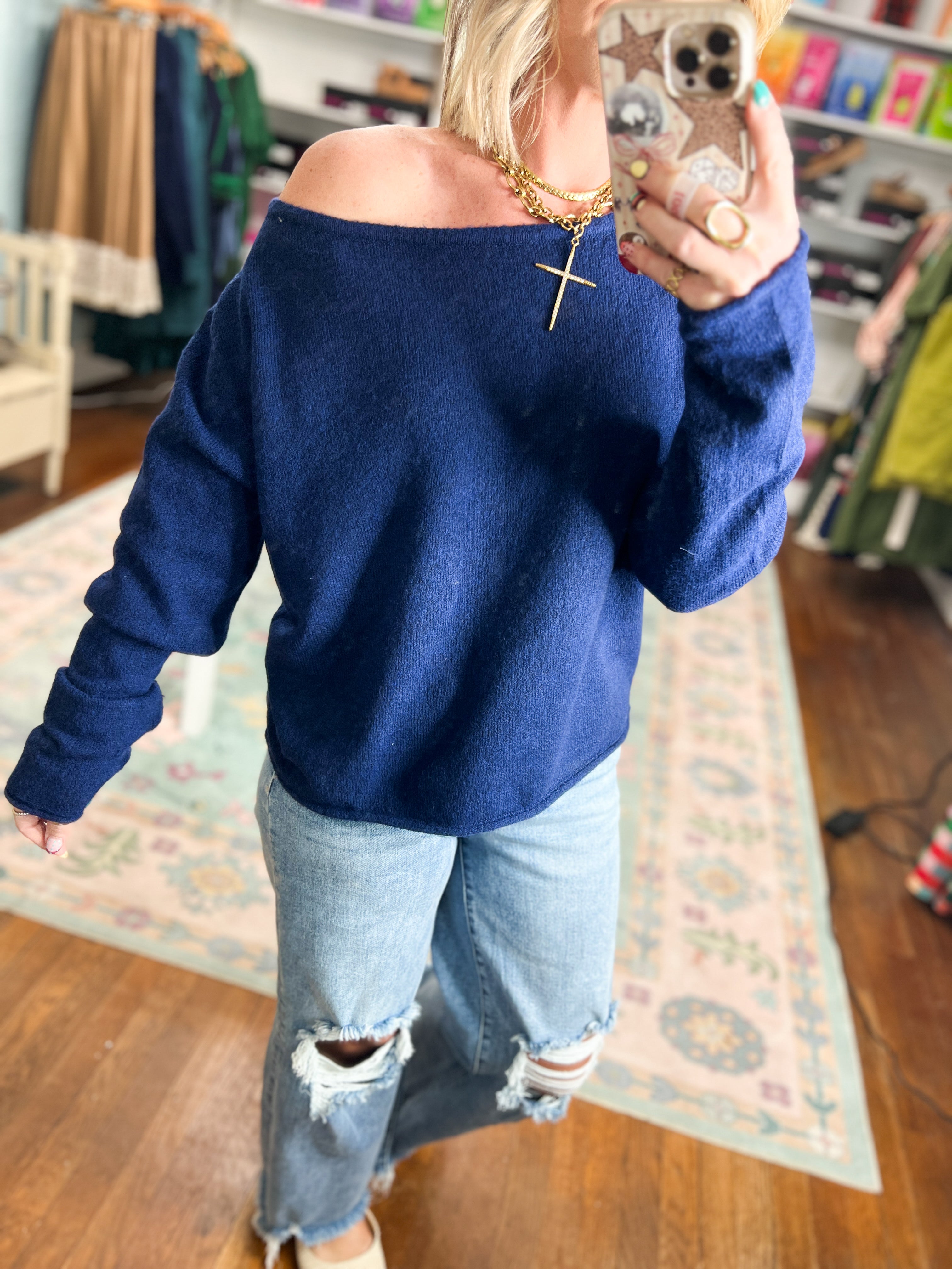 Navy off-shoulder sweater with gold cross detail at neckline